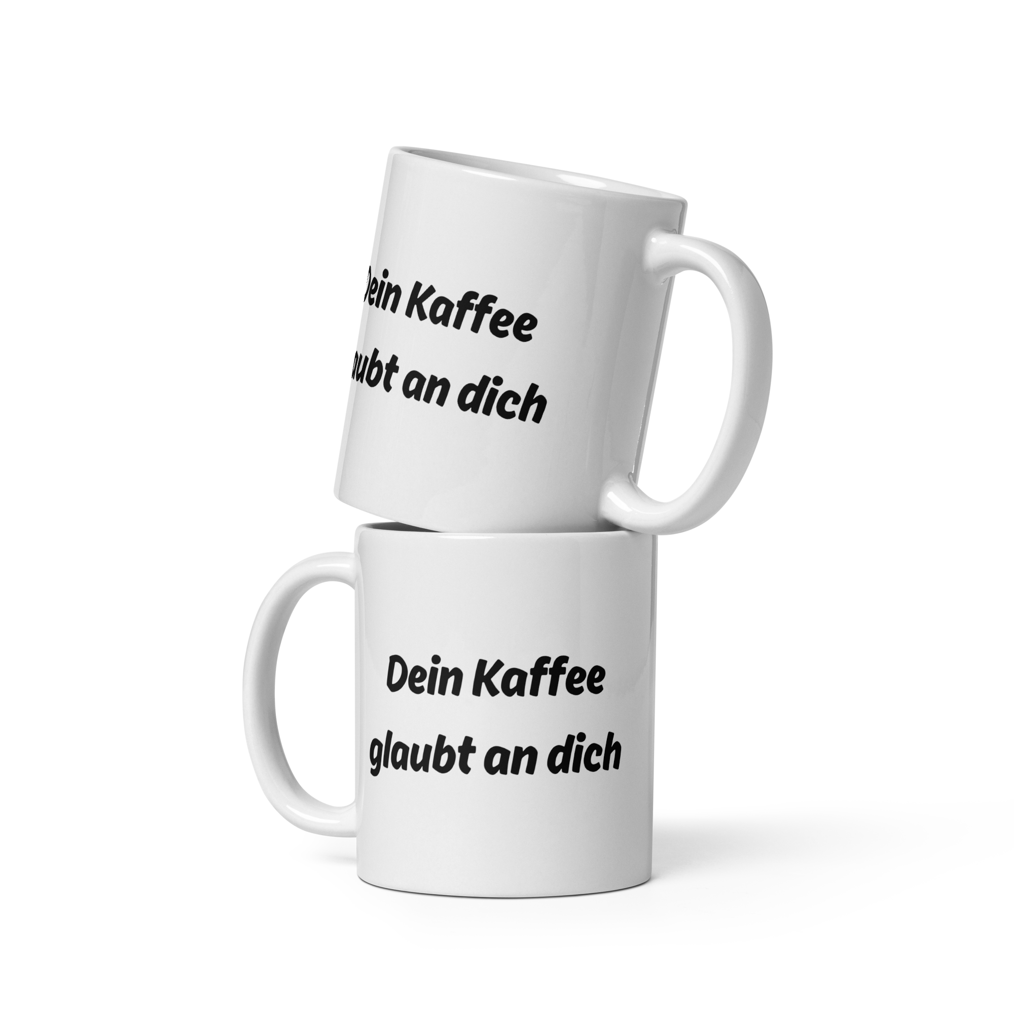 Zwei weiße Kaffeetassen mit schwarzem Spruch-Aufdruck ‚Dein Kaffee glaubt an dich‘, übereinandergestapelt.