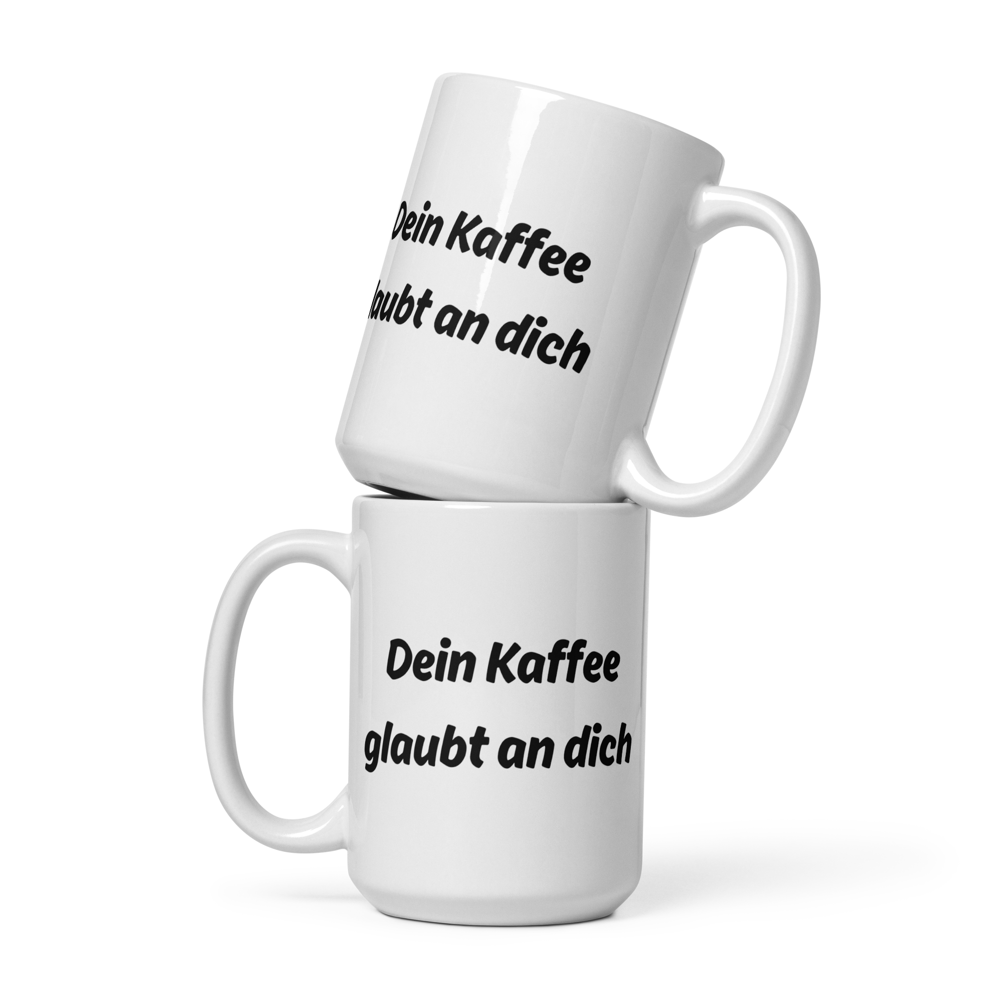 Zwei weiße Kaffeetassen mit schwarzem Spruch-Aufdruck ‚Dein Kaffee glaubt an dich‘, übereinandergestapelt.