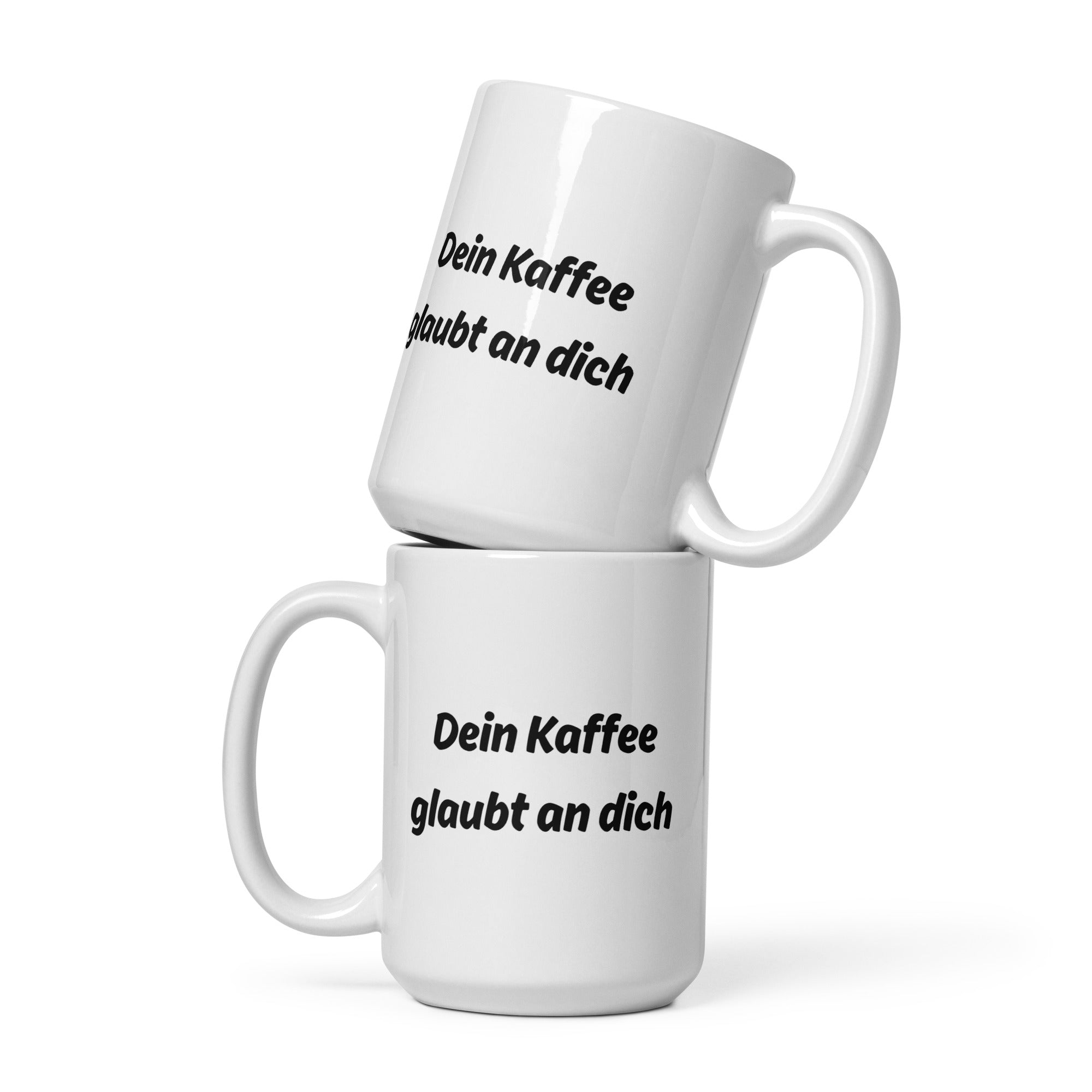 Zwei weiße Kaffeetassen mit schwarzem Schriftzug ‚Dein Kaffee glaubt an dich‘, übereinander gestapelt.