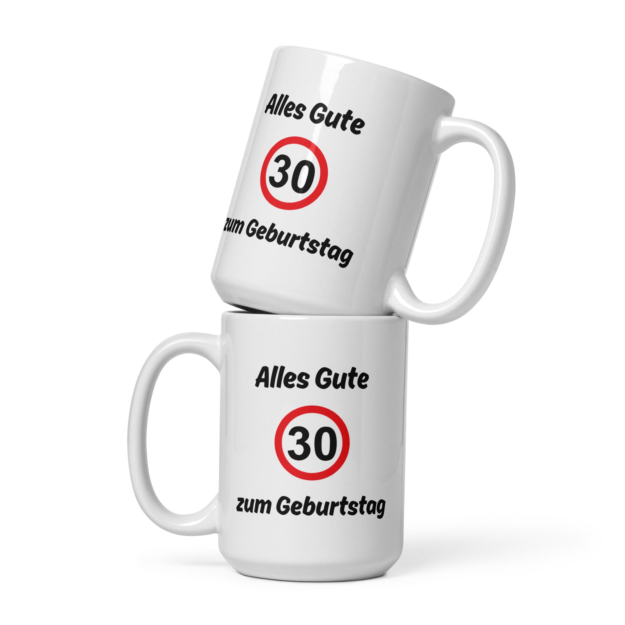 Zwei weiße Kaffeetassen mit schwarzer Aufschrift ‚Alles Gute zum Geburtstag‘ und rotem Verkehrszeichen mit Zahl 30, übereinandergestapelt.