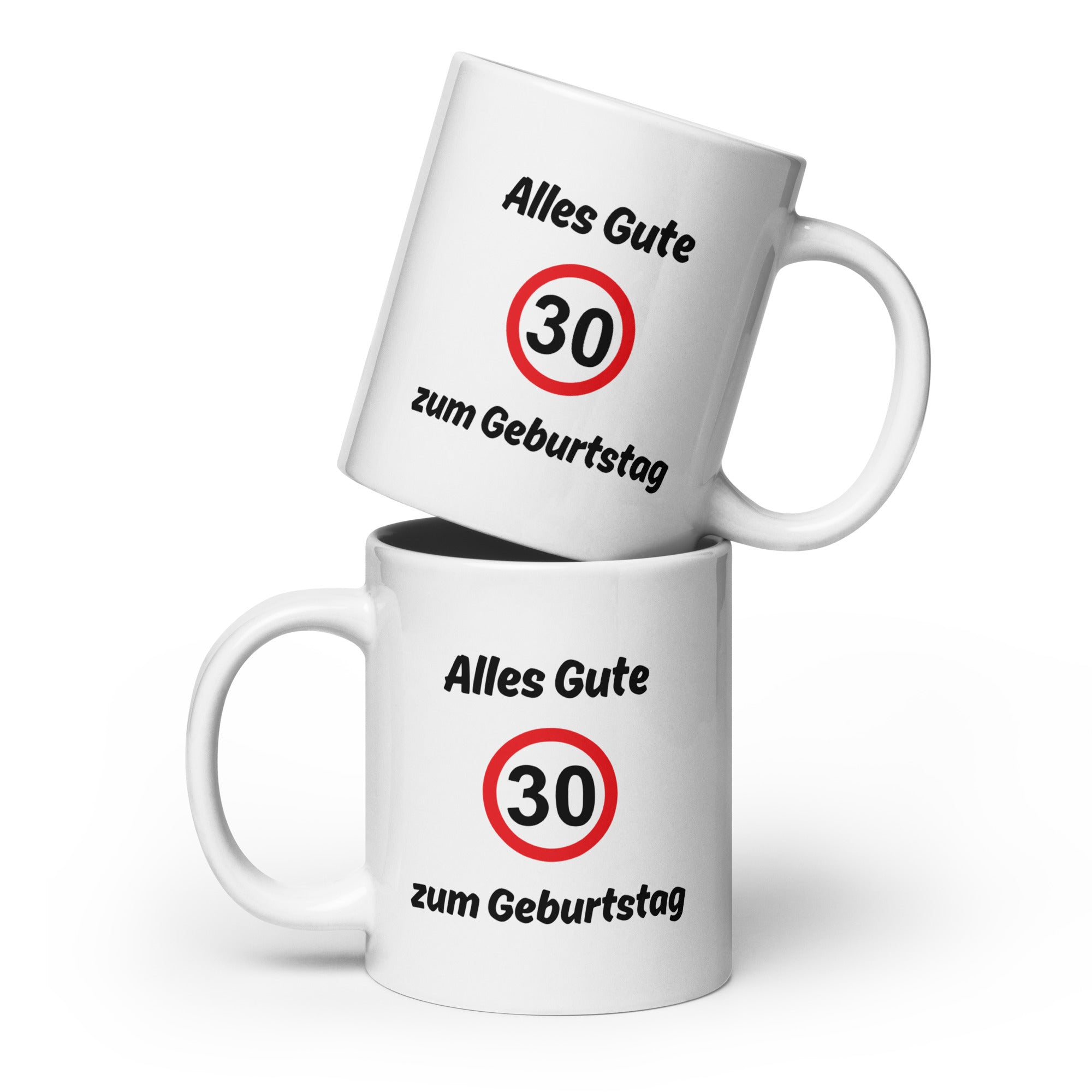 Zwei weiße Kaffeetassen mit schwarzer Aufschrift ‚Alles Gute zum Geburtstag‘ und rotem Verkehrszeichen mit Zahl 30, übereinandergestapelt.